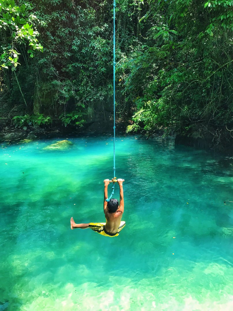 photo-of-boy-swinging-over-body-of-water-2413238